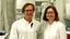 Two researchers wearing white lab coats are standing in a laboratory